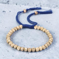 Pulsera de esferas doradas de talla diamantada sobre cordón trenzado azul