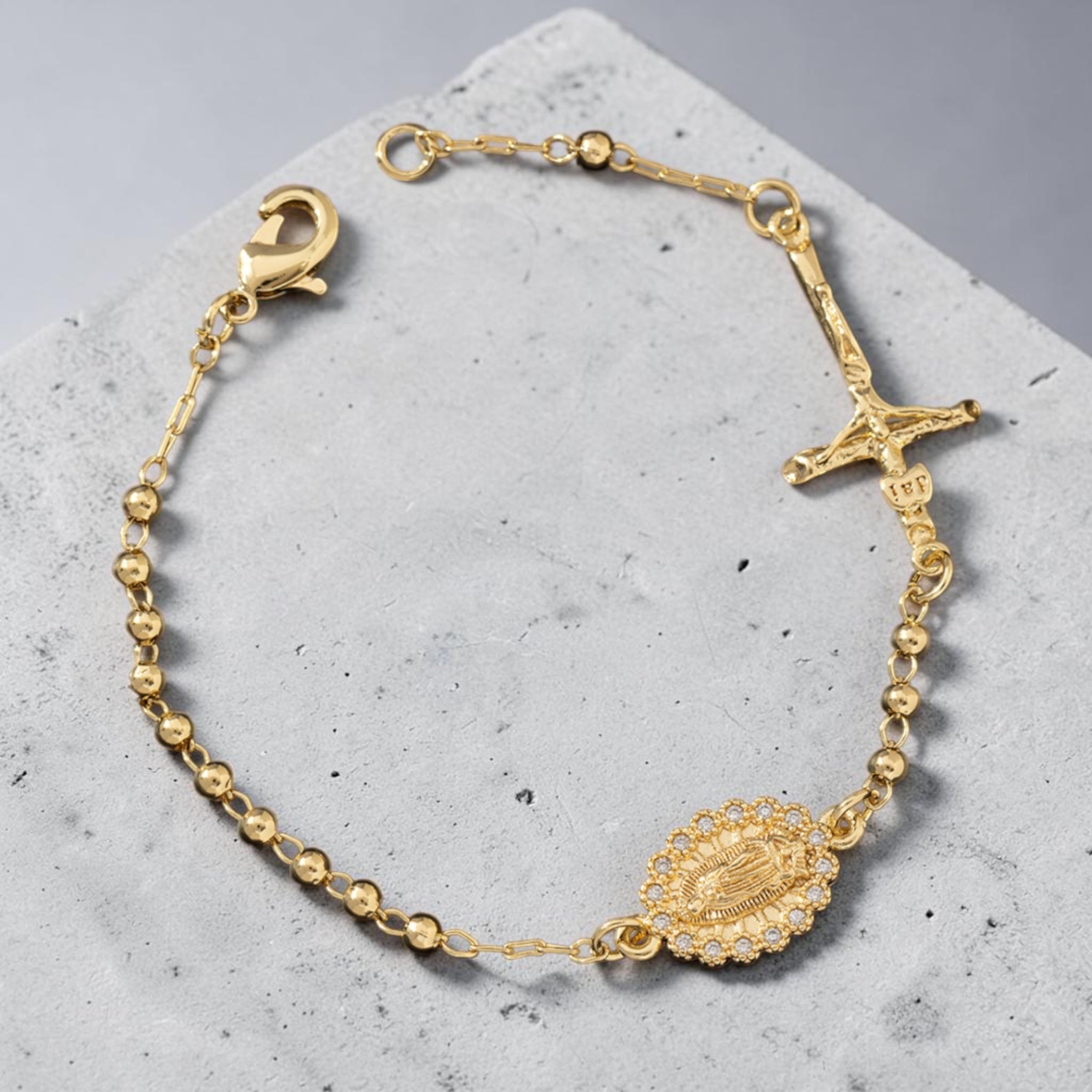 Pulsera rosario dorada de 3 mm con medalla y crucifijo sobre hormigón